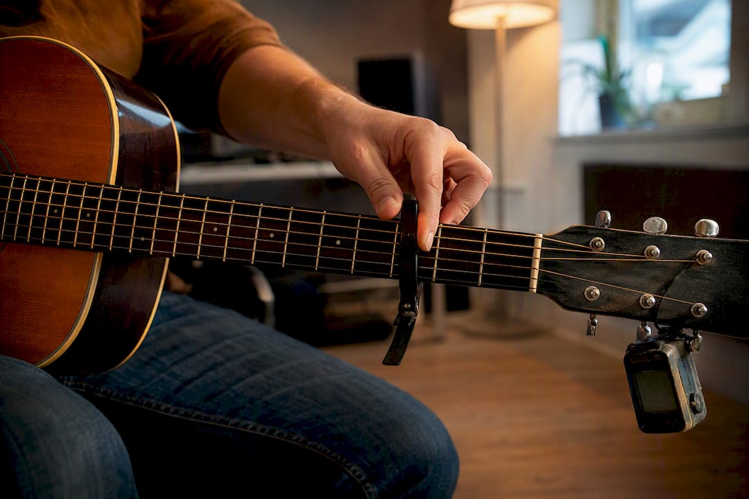 Hand die een capo op de toets van de gitaar plaatst