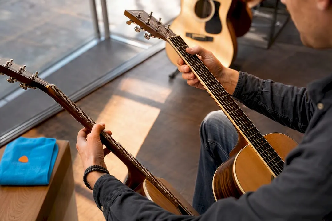 Beginnende gitarist vergelijkt twee akoestische gitaren in een muziekwinkel